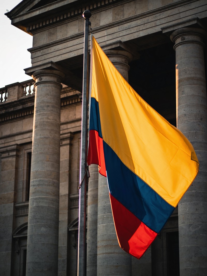 Fachada monumental de una alta corte colombiana con la bandera tricolor al atardecer