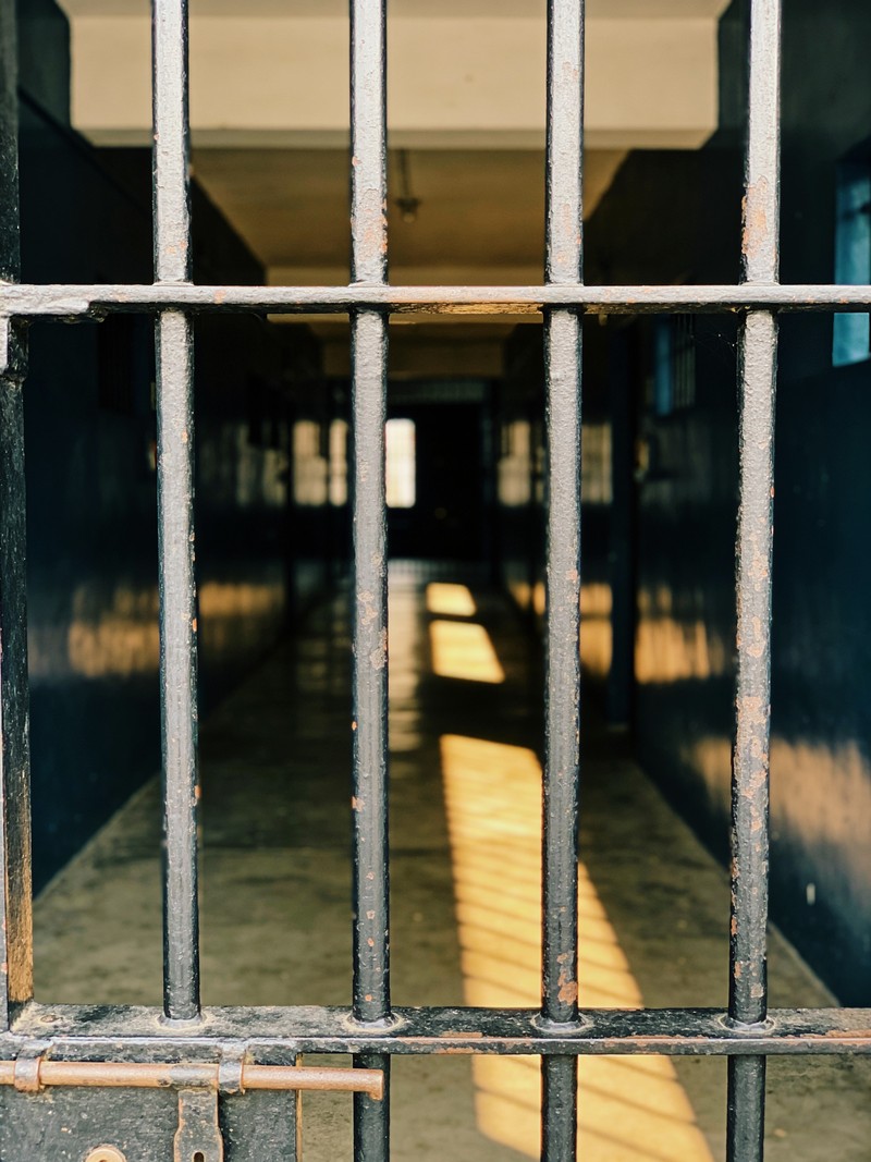 Barrotes de acero de un pabellón penitenciario con un haz de luz cálida atravesando el corredor